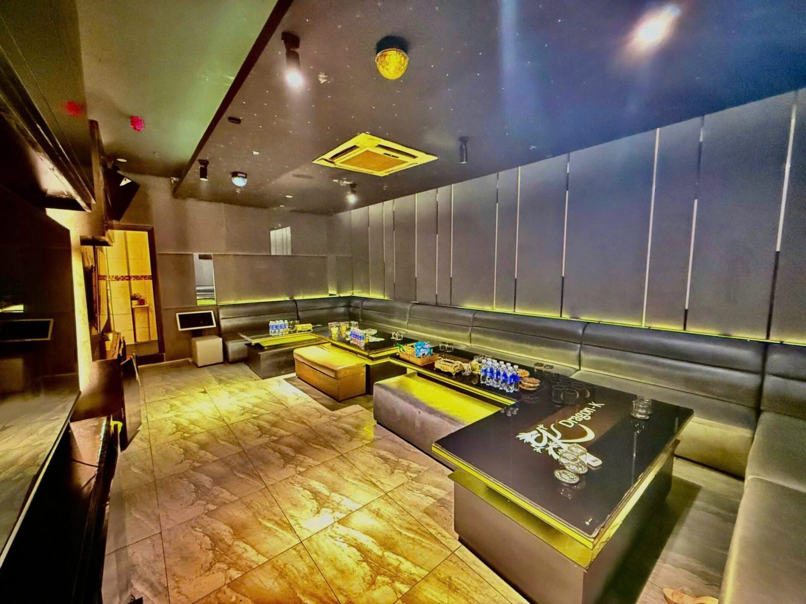 466 DRAGON K KTV 包厢：灰皮软包墙配金色灯带、星点天花，黑色茶几上印着 Dragon-K 金色龙纹