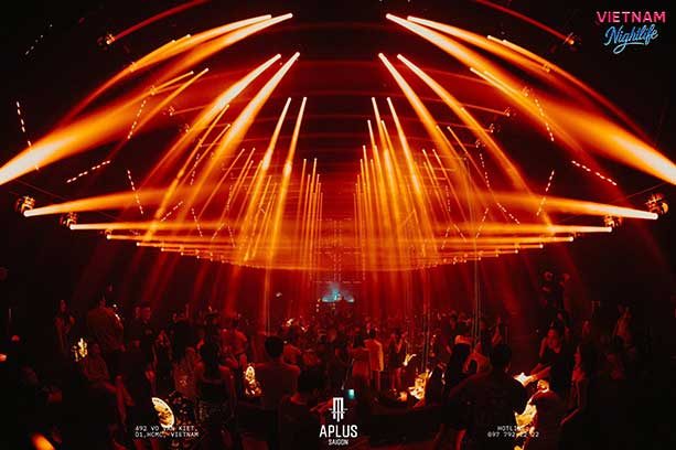 APLUS MUSIC SAIGON 橙色激光在头顶铺成扇形光阵，覆盖整个舞池与后排卡座
