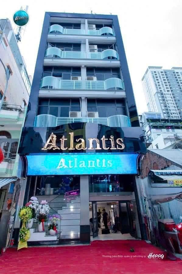 ATLANTIS KTV 胡志明第一郡门头，金色 Atlantis 招牌与蓝色海浪 LED 灯箱，红毯入口