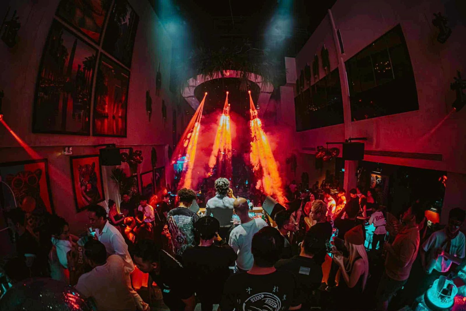 BAIA SAIGON 夜店主厅，DJ 岛两侧喷出橙红火柱与 CO2 烟雾，人群站满台前