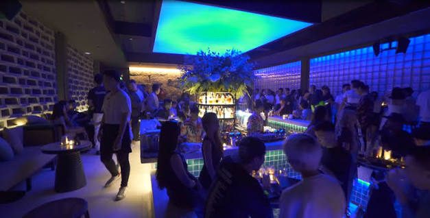 BAM BAR 蓝绿灯光时段:客人沿水池边走动,中央吧台与酒架被蓝光包围