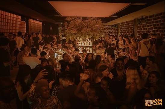 BAM BAR 暖琥珀灯光的爆满夜场:干花装置悬在中央酒架上方,全场人挤人