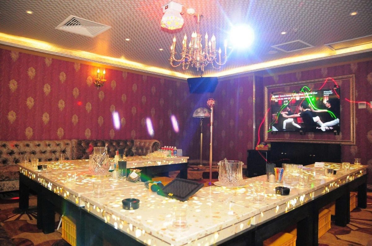 BOSS KTV 包厢：玫红暗纹墙、浅蓝软包、鎏金水晶吊灯与发光长台