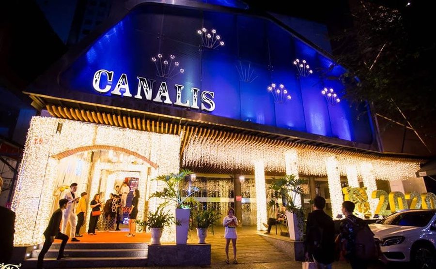 CANALIS CLUB 门头 · 深蓝色曲面外墙上白色 CANALIS 灯字，雨帘式暖白灯串包住整个入口