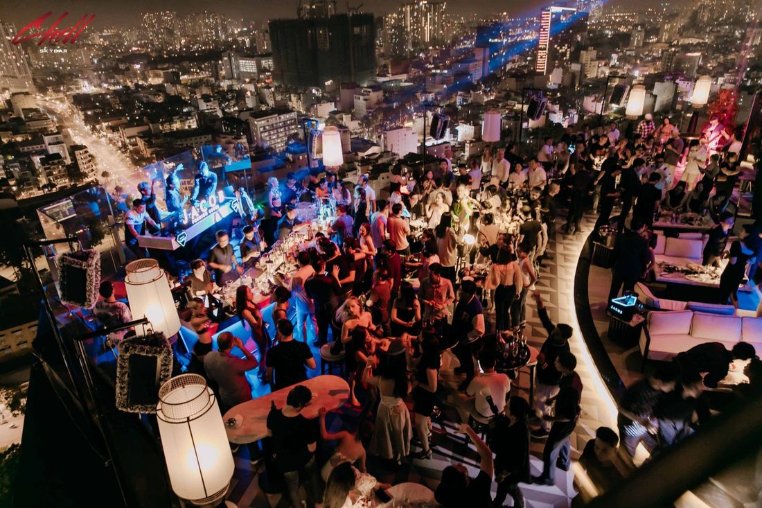 CHILL SKY BAR 天台全景俯拍,DJ 台亮蓝色灯光,人群在吧台前跳舞,右侧是白色沙发卡座区