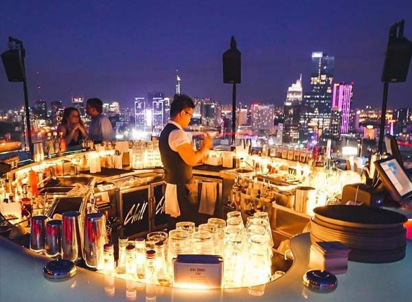 CHILL SKY BAR 吧台特写,一整排蜡烛、玻璃杯与酒瓶,调酒师在吧台内工作