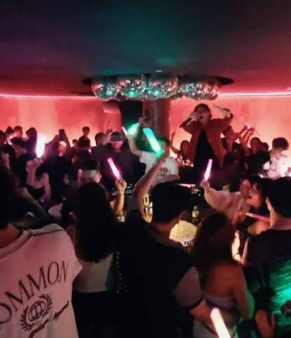 FETTI BAR 高峰时段人群举着荧光棒，中央平台上有人拿麦克风唱