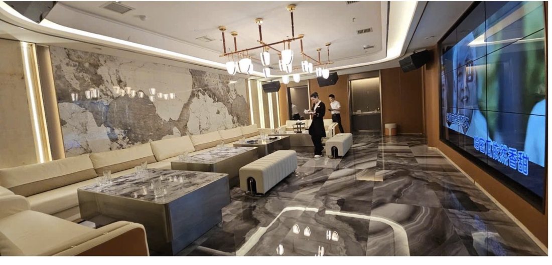 金爵会所长厅包厢:整幅天然石材背景墙、线性吊灯、灰白大理石地面与奶白长沙发