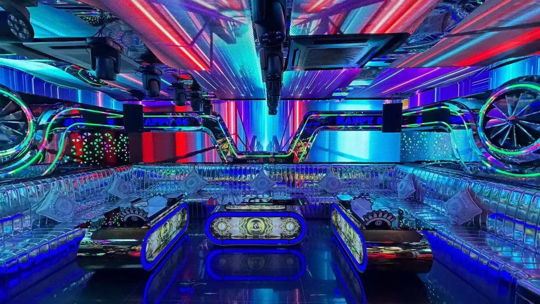 HAPPY 65 KTV 赛博车轮包厢:天花 LED 条屏斜扫光,两侧巨型发光车轮,三张胶囊形茶几