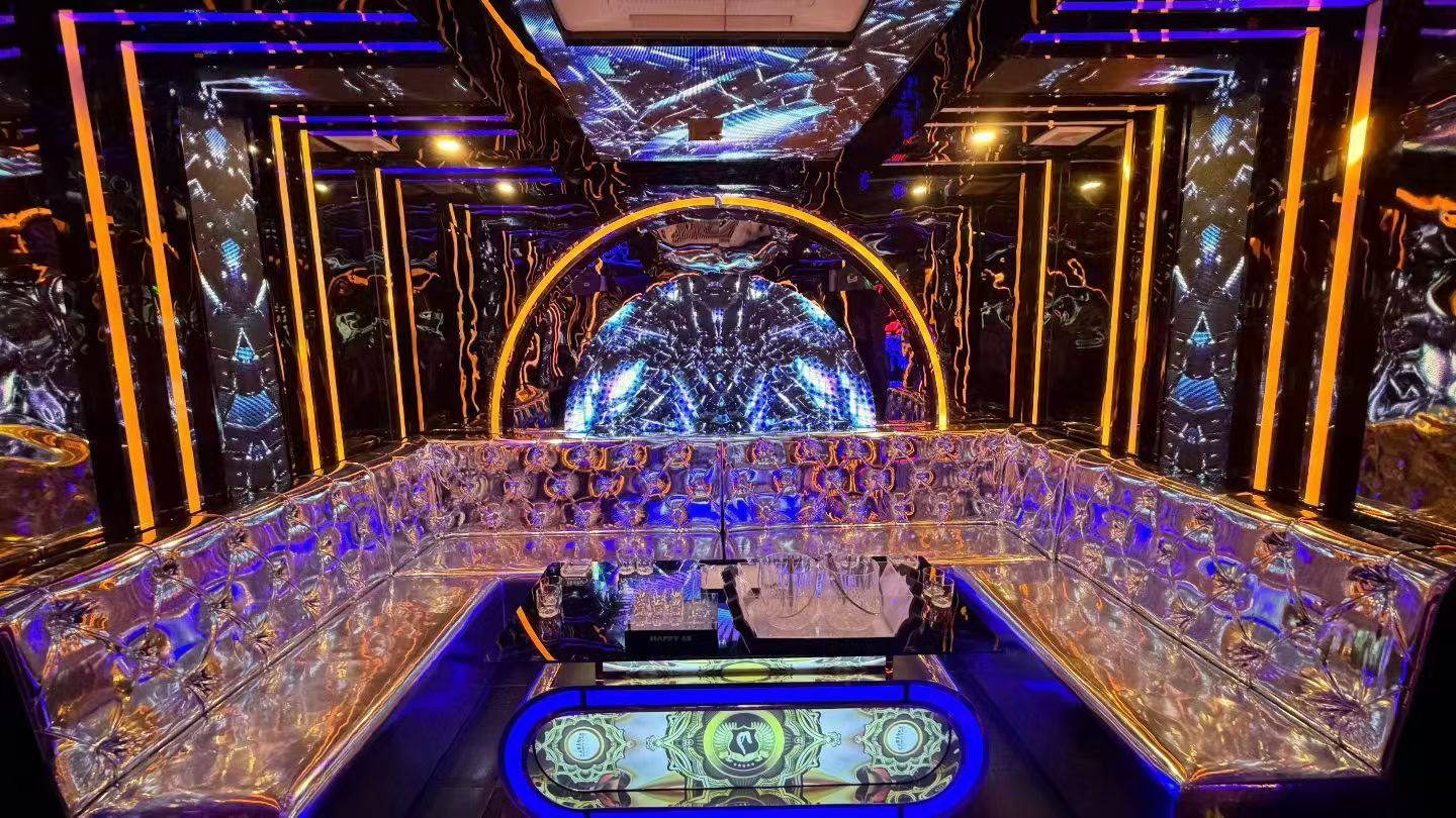 HAPPY 65 KTV 胡志明第五郡包厢：金橙灯管立柱、拱形万花筒 LED 屏与香槟金绗缝环形卡座