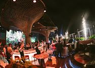 KÉN SKYBAR 入夜时段：伞状雕塑打光，客人围着高台交谈，绿色 LED 屏做背景