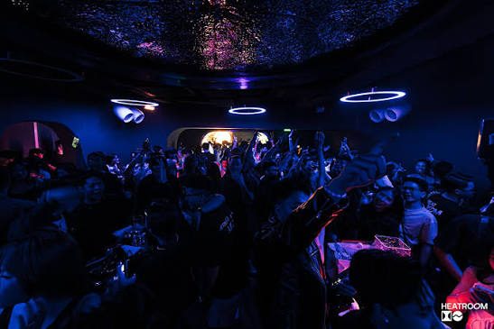 LOCO HEATROOM BAR 全景，蓝紫灯光下满场人群，天花板打着碎星投影与环形灯