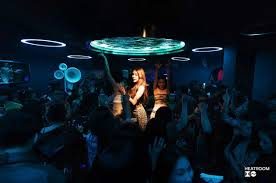 LOCO HEATROOM BAR 表演时段，女歌手站在圆形灯台下，人群围成一圈