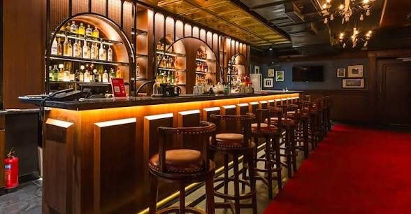 NEIGHBORHOOD BAR 拱形酒柜吧区：皮质高脚凳、吊灯与红地毯