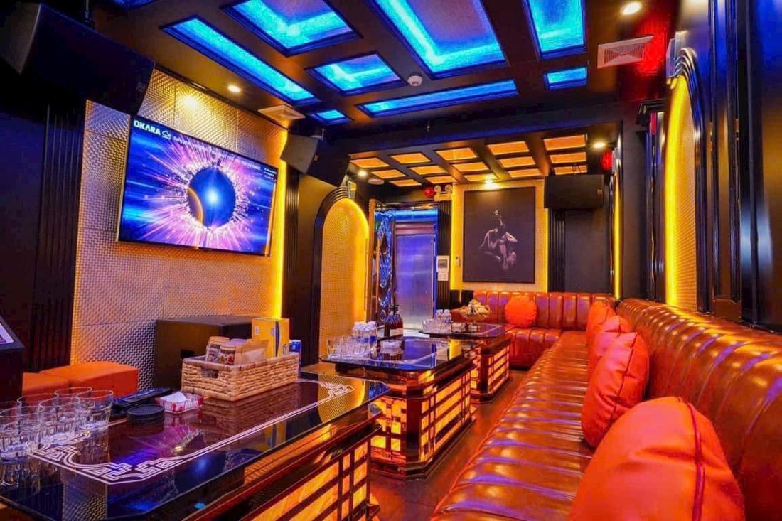 SAIGON STAR KTV 长条形包厢：橙棕皮长卡座、蓝色与琥珀色双段格栅灯天花、金织纹墙面