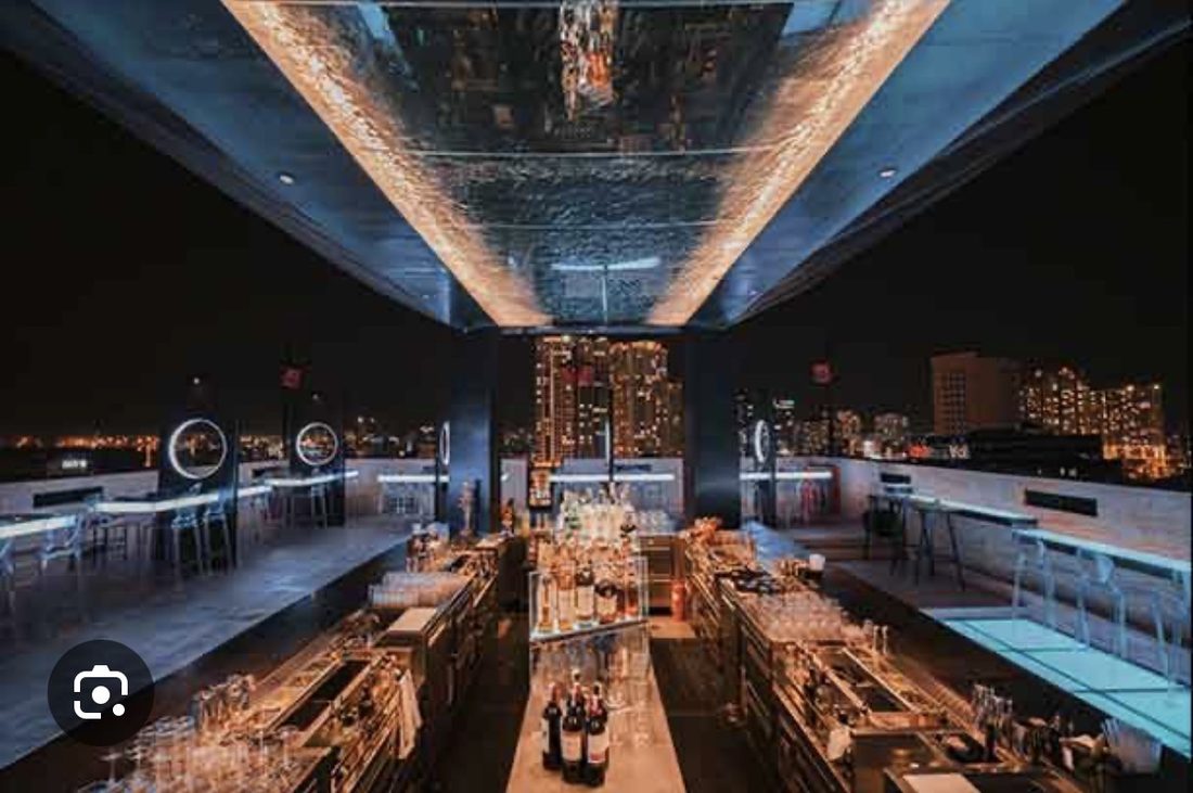 ZION 吧台中轴俯视:整排酒瓶与杯具,镜面天花把灯光映成一层碎金